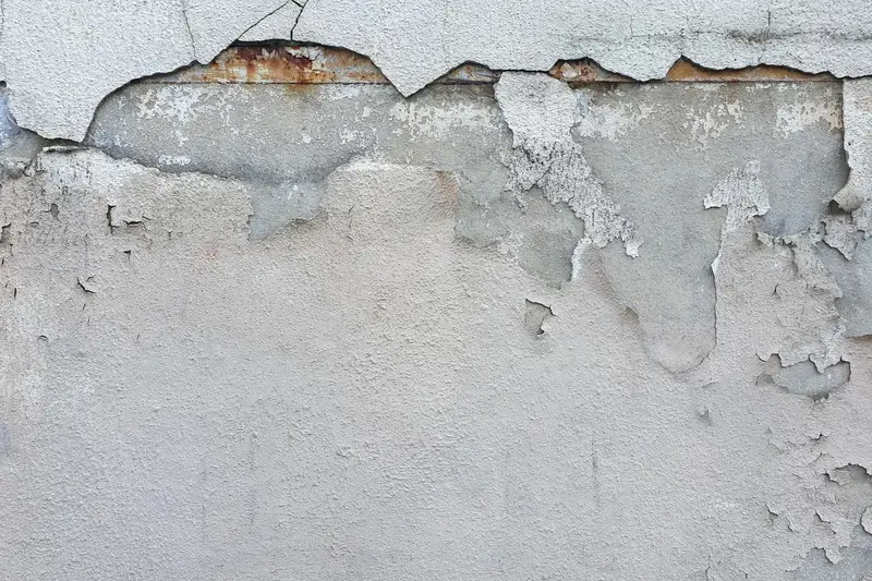 Bas de mur dont l'enduit s'effrite sous l'humidité